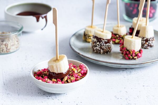 Banán namočte v čokoládě a následně ve směsi nasekaných oříšků a lyo ovoce.